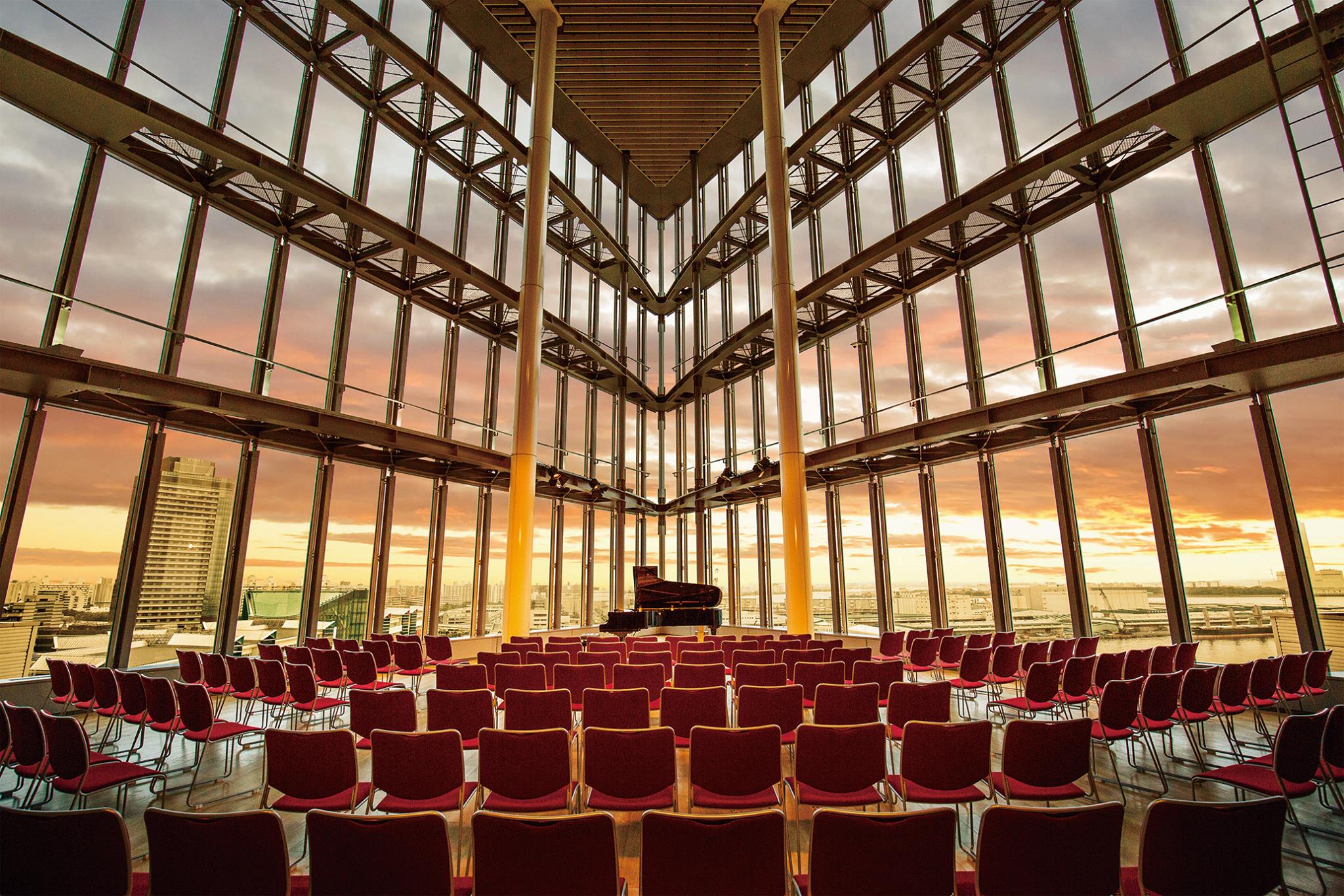 Conference attendees viewing Osaka Bay sunset through floor-to-ceiling glass walls at Sunset Hall event venue